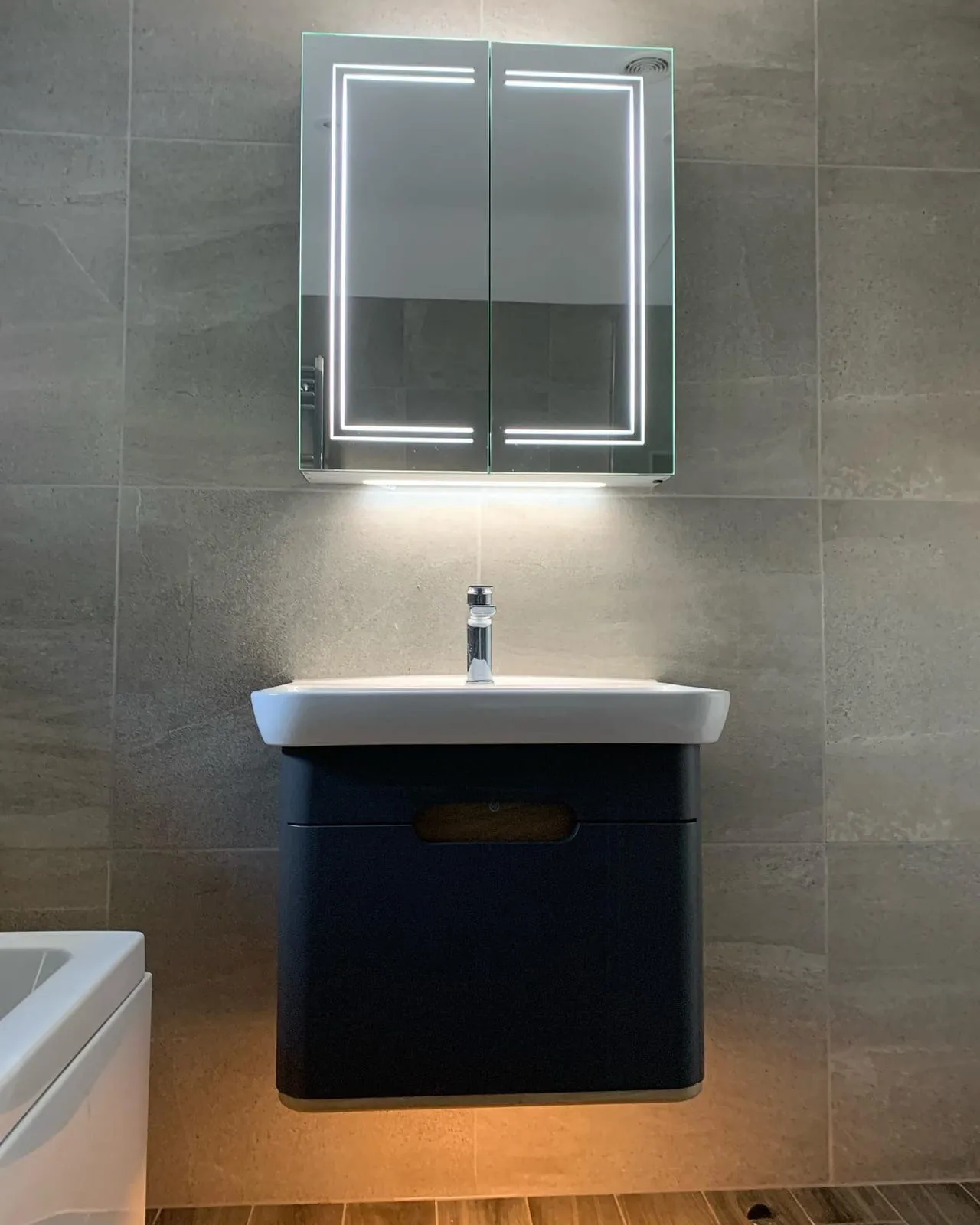 A basin set on a navy wall-hung vanity unit with a mirror above it