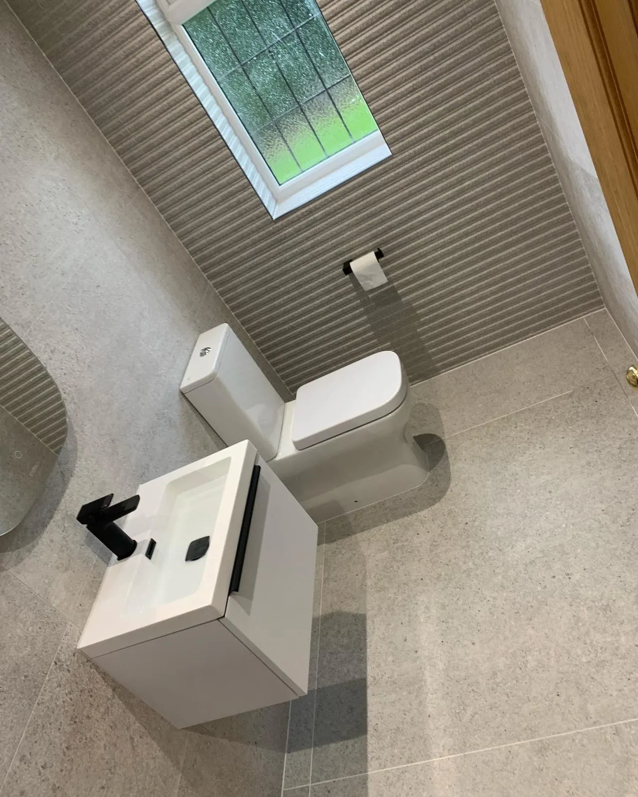 A wall-hung basin with a black tap next to a back-to-wall toilet, seen from above