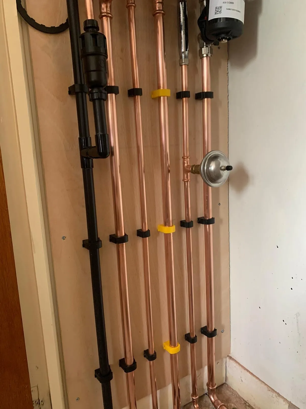 Copper pipework run in parallel up a wall, clipped at even spacings