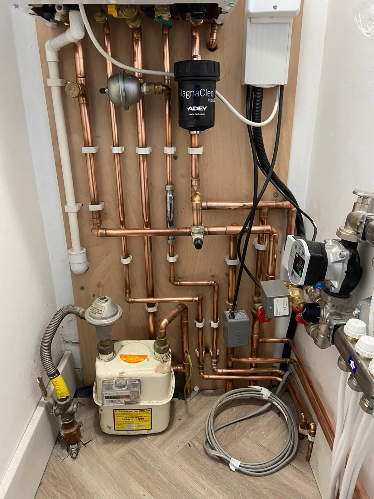 Copper pipework, a pump and the system controls built up on a plant room wall