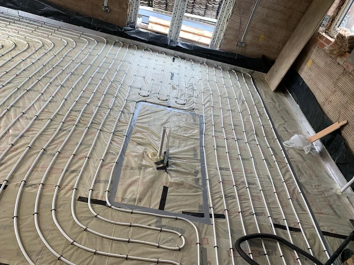 Underfloor heating pipe laid over a membrane, set out before the floor build-up goes down
